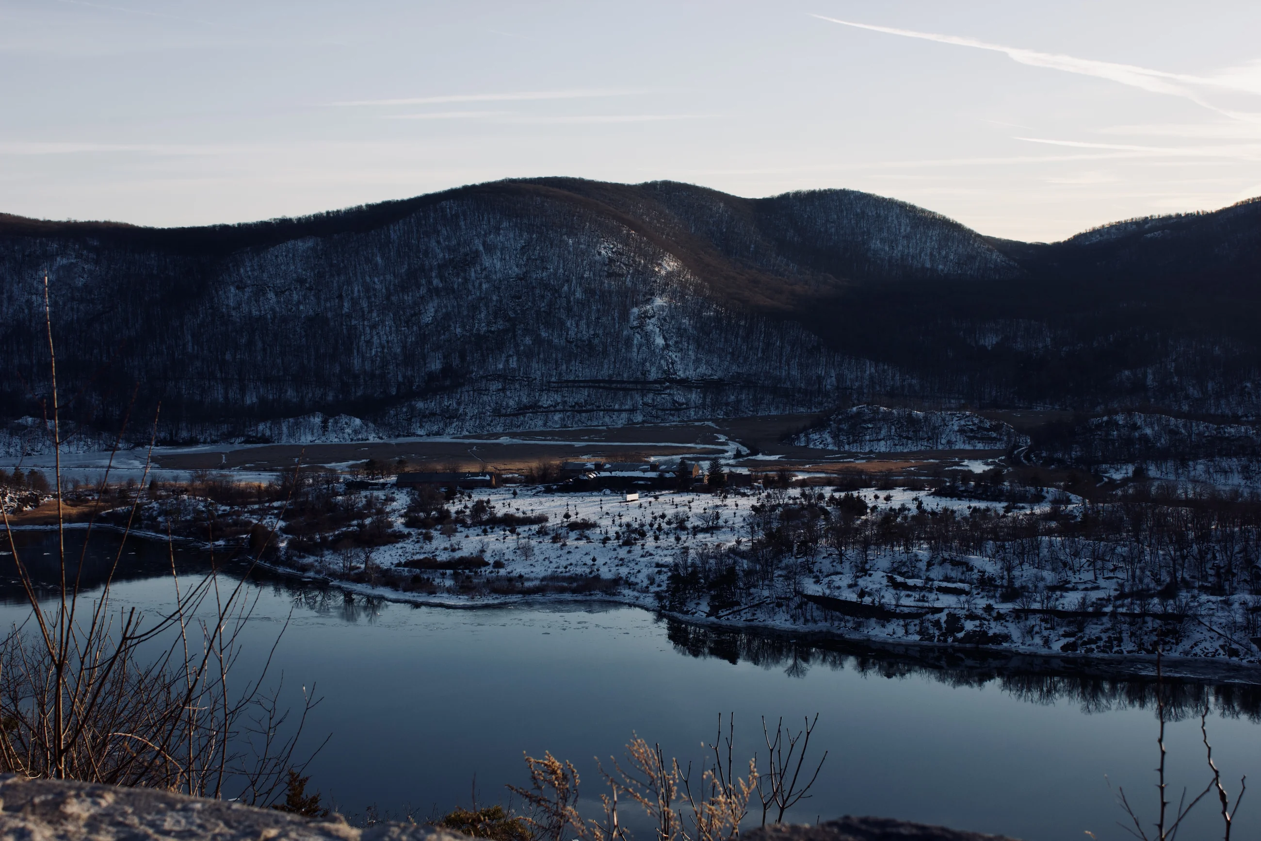 Snowy river valley below dark hills