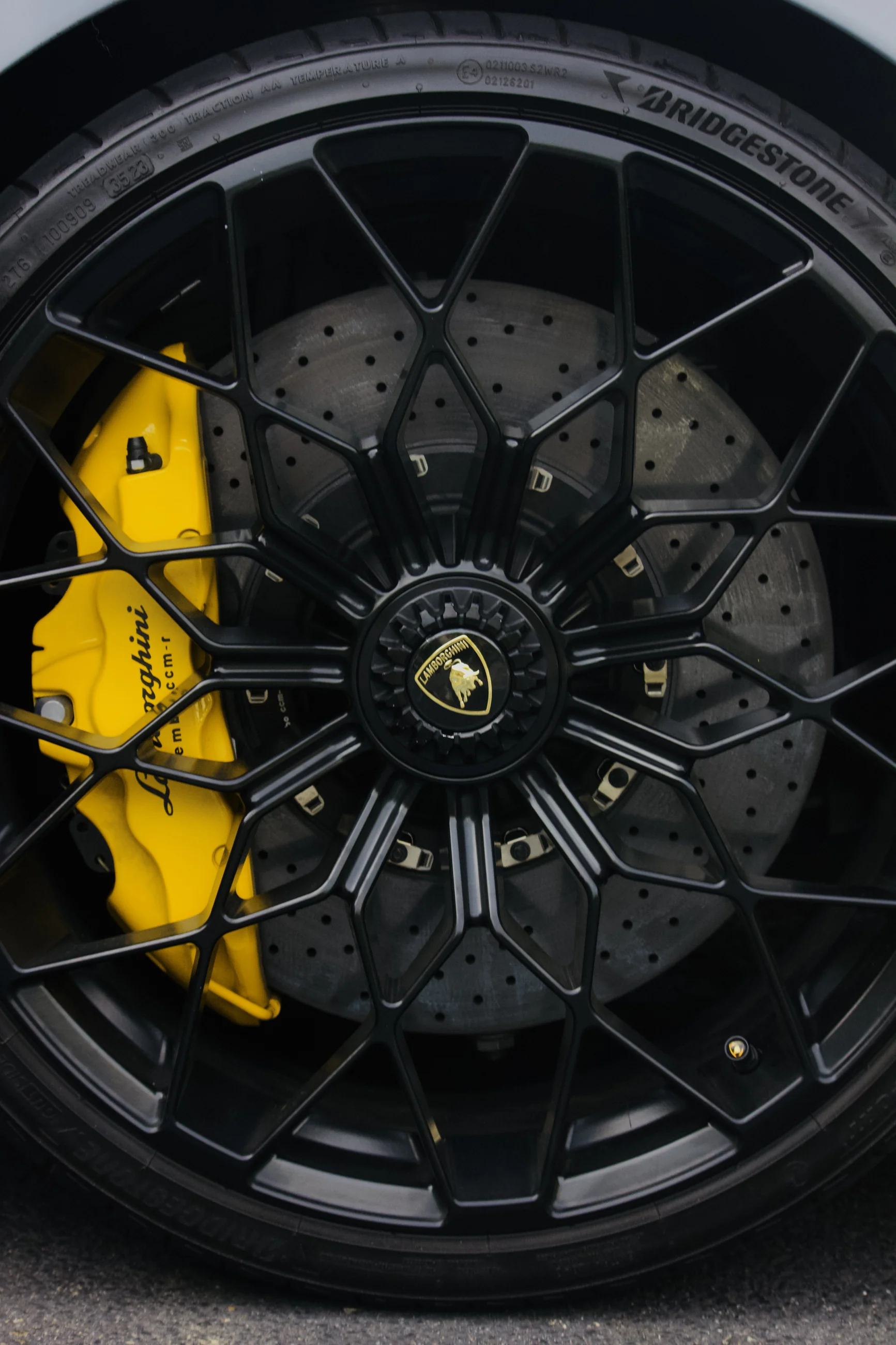 Black Lamborghini wheel with a bright yellow brake caliper